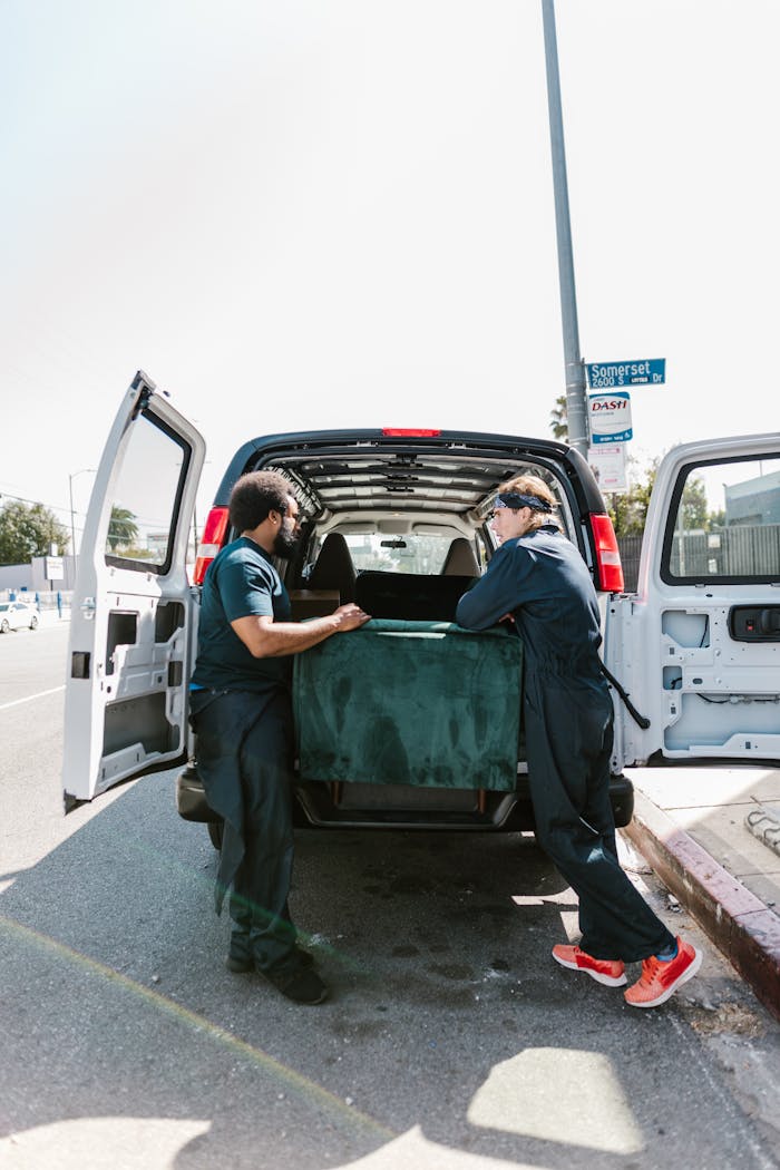 about-us-02 Two movers load a van with furniture during moving day.